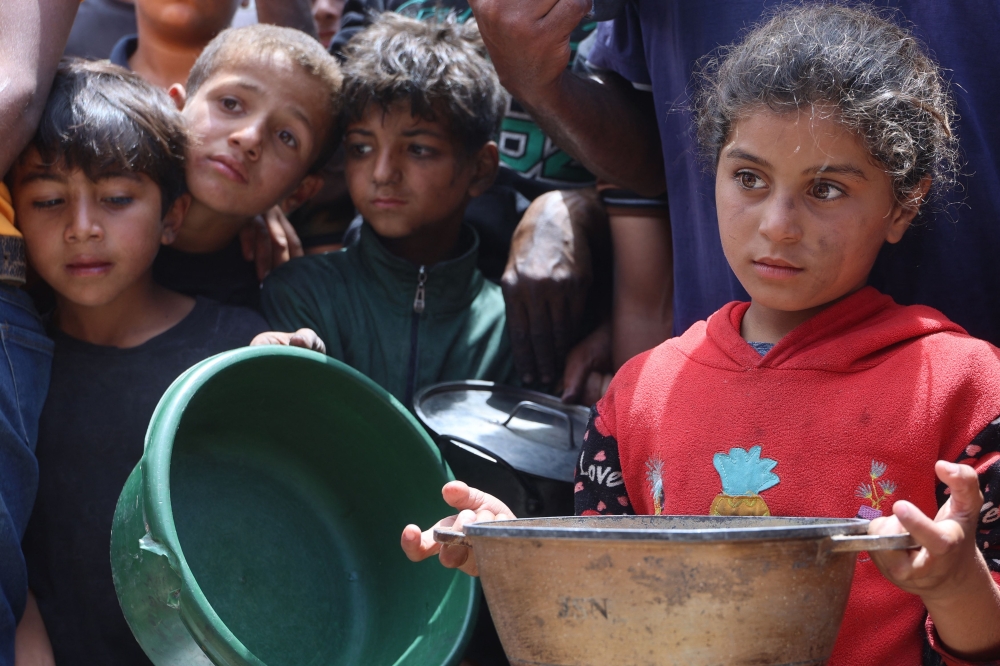 Palestinian children wait in front of a hot meal distribution truck at a displacement camp near Gaza City's port on Thursday. - AFP