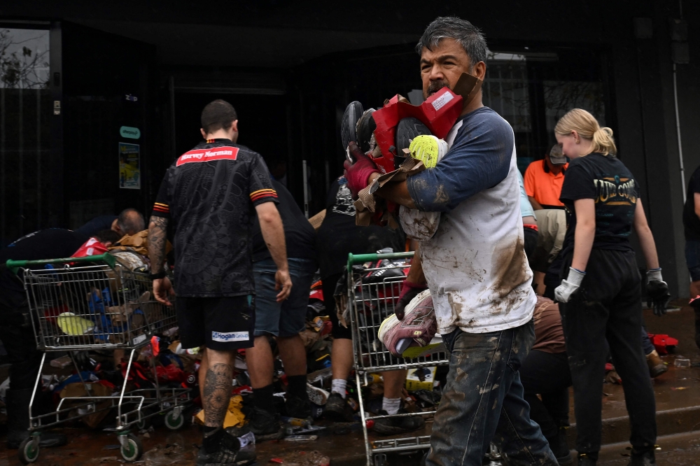 Volunteers clear flood-damaged goods from their shops along the banks of the Manning River in Taree. — AFP
