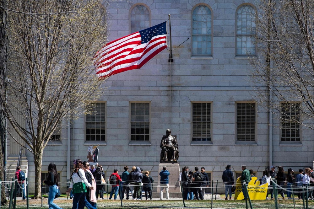 Students stand around the John Harvard Statue in Harvard Yard, at Harvard University in Cambridge, Massachusetts. — AFP 