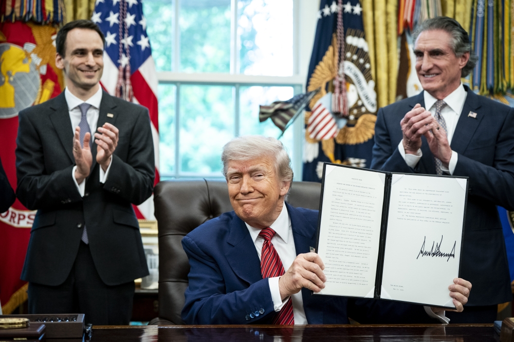 President Donald Trump signs executive orders in the Oval Office of the White House in Washington.