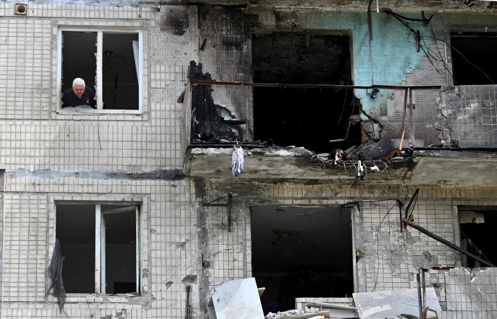 A local resident looks out of the window of his flat in a multistorey residential building, in Kyiv. — AFP