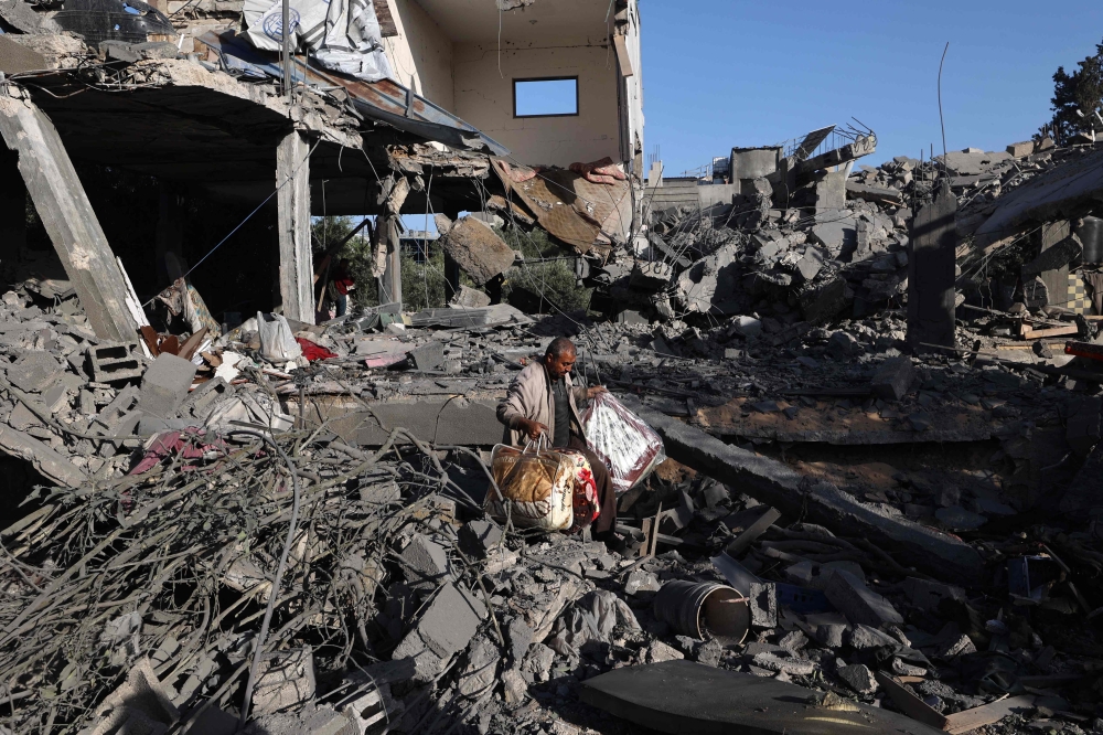 A Palestinian man carries items he salvaged from a house targeted in an Israeli strike at the Nuseirat camp. — AFP