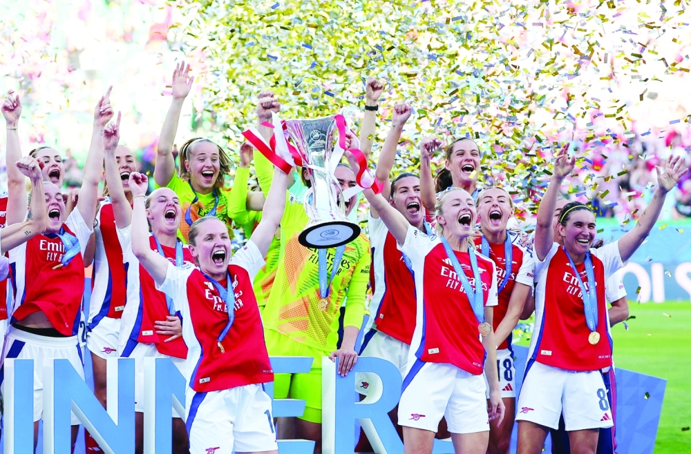 Arsenal's Kim Little and Leah Williamson lift the trophy to celebrate with teammates after winning the Women's Champions League. — Reuters