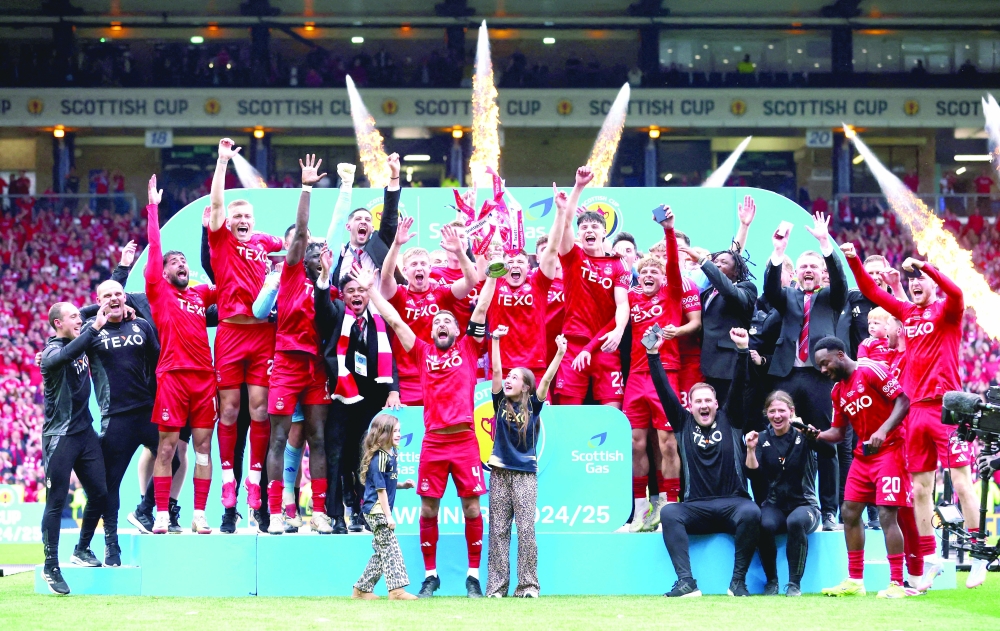 Aberdeen's Graeme Shinnie lifts the trophy with teammates after winning the Scottish Cup Final. — Reuters