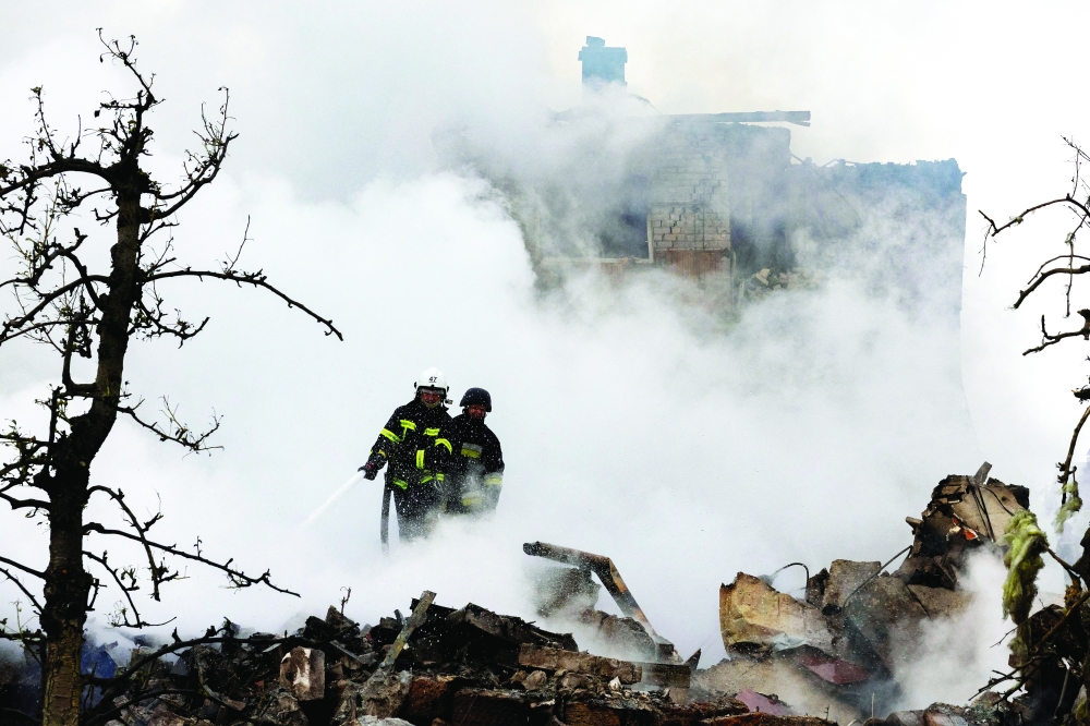 Emergency workers extinguish fire of a private house that was destroyed in a Russian rocket strike, in Markhalivka, Kyiv. — Reuters