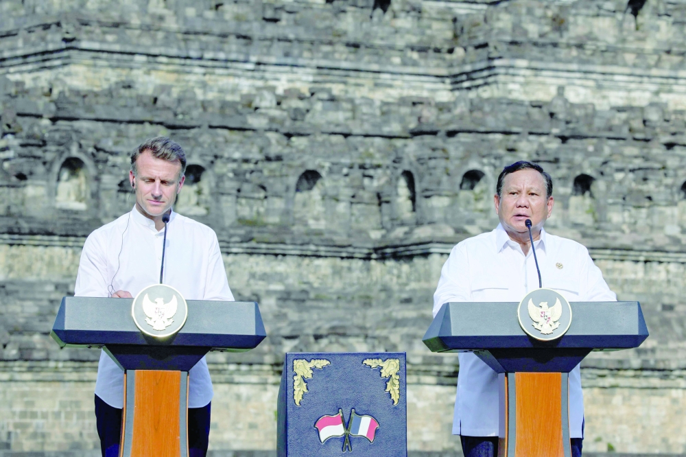 France's President Emmanuel Macron (L) and Indonesian President Prabowo Subianto speak during a visit at Borobudur Temple, in Magelang. — AFP