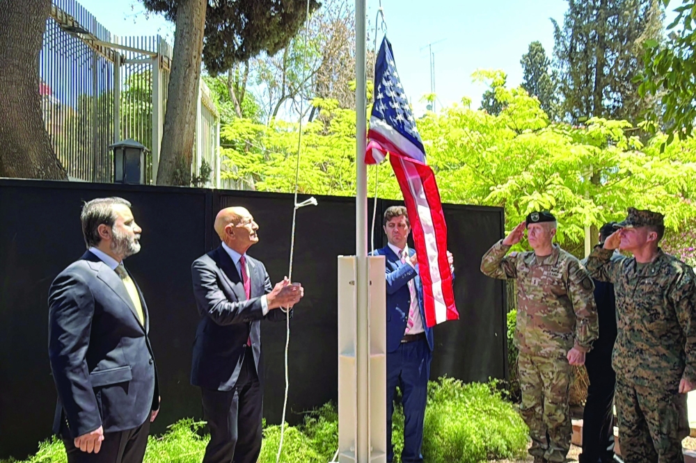 Syrian FM Asaad al Shibani (L) looks on as US special envoy for Syria,Thomas Barrack, raises the flag of the US at the ambassador's residence in Damascus. — AFP