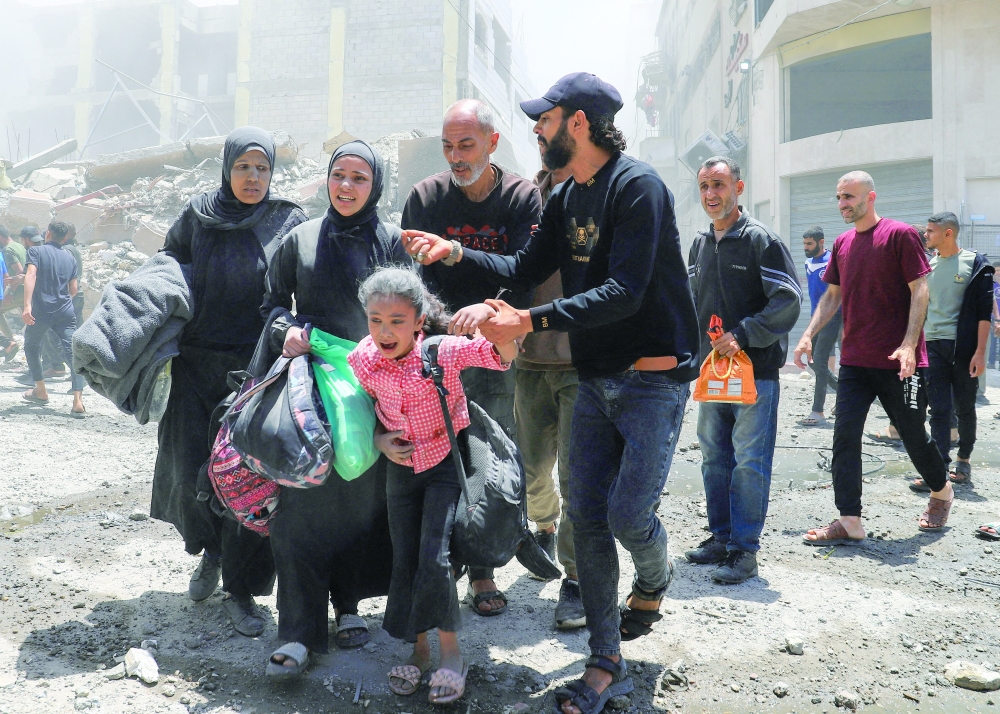 Palestinians evacuate in the aftermath of an Israeli strike on a house, in Gaza City, on Friday. — Reuters