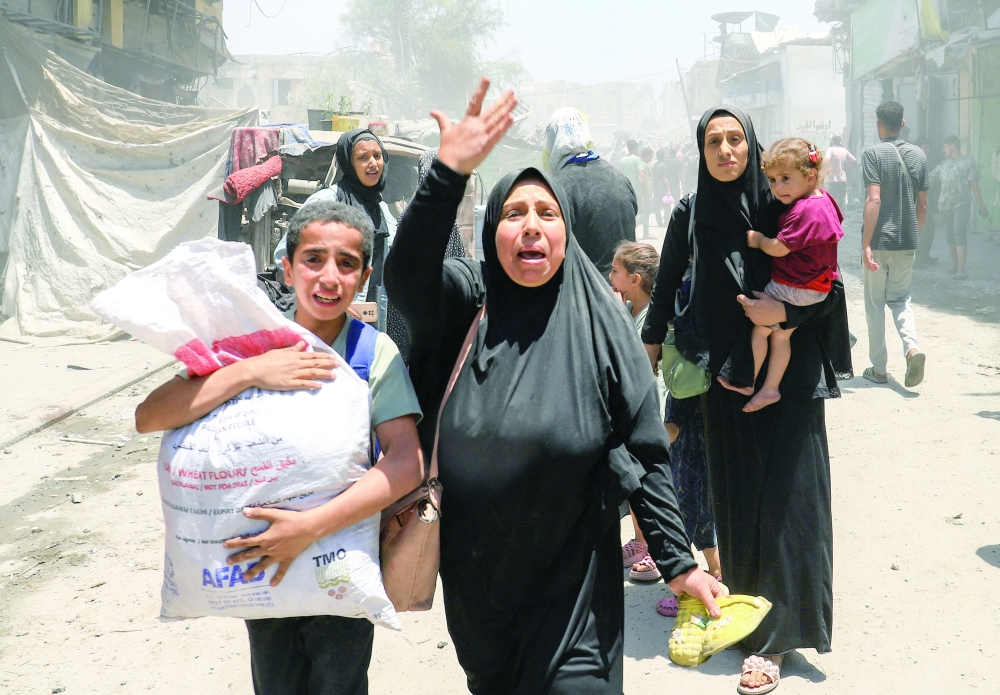 Palestinians evacuate in the aftermath of an Israeli strike on a house, in Gaza City, on Friday. — Reuters