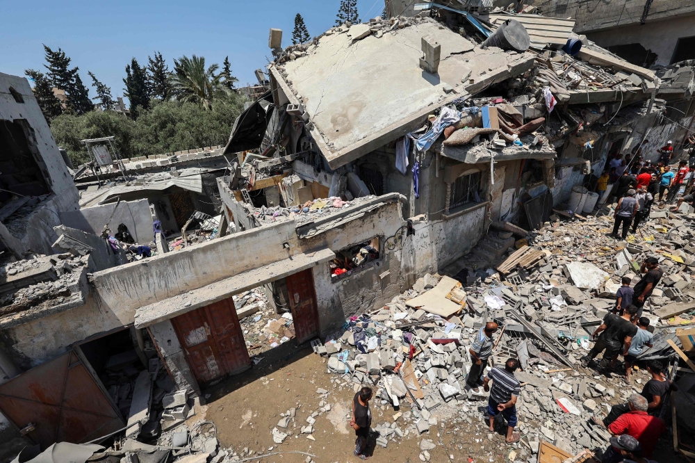 People inspect the damage at the site of an Israeli strike, in the central Gaza Strip. — AFP