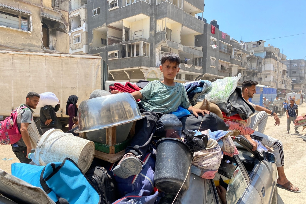 A boy sits with packed belongings and beddings atop a moving vehicle as displaced people flee from Khan Yunis westwards to al-Mawasi in the southern Gaza Strip on June 3, 2025 after the Israeli military had issued an evacuation order the previous day.  (Photo by AFP)

