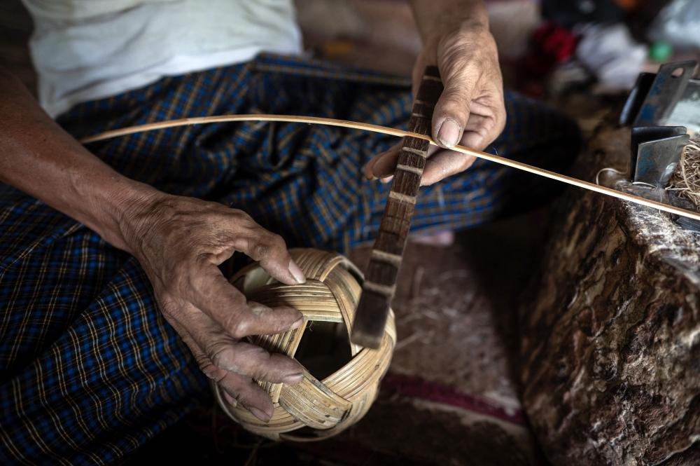 This photo taken on May 8, 2025 show a man weaving cane into a chinlone ball, used in the ancient Myanmar game considered a blend between sport and art, at a workshop in Hinthada township in the Irrawaddy delta region.  Mastering control of the rising and falling rattan chinlone ball teaches patience, says a veteran of the traditional Myanmar sport -- a quality dearly needed in the long-suffering nation.
 - To go with 'MYANMAR-SPORT-CULTURE-CONFLICT-CHINLONE,FOCUS' by Lynn MYAT and Hla-Hla HTAY
 (Photo by Sai Aung MAIN / AFP) / To go with 'MYANMAR-SPORT-CULTURE-CONFLICT-CHINLONE,FOCUS' by Lynn MYAT and Hla-Hla HTAY


