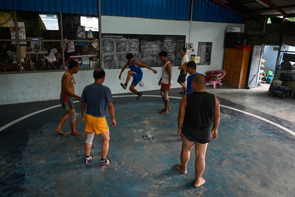 This photo taken on May 13, 2025 shows players taking part in a game of the traditional Myanmar sport of chinlone at a court in Yangon. Mastering control of the rising and falling rattan chinlone ball teaches patience, says a veteran of the traditional Myanmar sport -- a quality dearly needed in the long-suffering nation.
 - To go with 'MYANMAR-SPORT-CULTURE-CONFLICT-CHINLONE,FOCUS' by Lynn MYAT and Hla-Hla HTAY
 (Photo by Sai Aung MAIN / AFP) / To go with 'MYANMAR-SPORT-CULTURE-CONFLICT-CHINLONE,FOCUS' by Lynn MYAT and Hla-Hla HTAY

