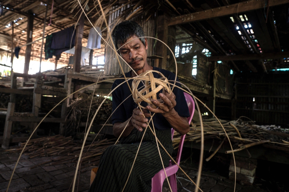 This photo taken on May 8, 2025 show a man weaving cane into a chinlone ball, used in the ancient Myanmar game considered a blend between sport and art, at a workshop in Hinthada township in the Irrawaddy delta region.  Mastering control of the rising and falling rattan chinlone ball teaches patience, says a veteran of the traditional Myanmar sport -- a quality dearly needed in the long-suffering nation.
 - To go with 'MYANMAR-SPORT-CULTURE-CONFLICT-CHINLONE,FOCUS' by Lynn MYAT and Hla-Hla HTAY
 (Photo by Sai Aung MAIN / AFP) / To go with 'MYANMAR-SPORT-CULTURE-CONFLICT-CHINLONE,FOCUS' by Lynn MYAT and Hla-Hla HTAY

