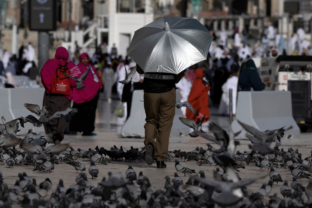 A policeman walks with an umbrella to escape from extreme weather at the grand mosque during the annual hajj pilgrimage in the holy city of Mecca, Saudi Arabia, June 3, 2025. Saudi Press Agency/Handout via REUTERS THIS IMAGE HAS BEEN SUPPLIED BY A THIRD PARTY.
