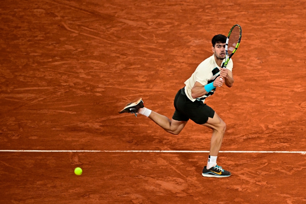 Spain's Carlos Alcaraz plays a backhand return to Italy's Lorenzo Musetti during their men's singles semi-final match on day 13 of the French Open tennis tournament on Court Philippe-Chatrier at the Roland-Garros Complex in Paris on June 6, 2025.  (Photo by JULIEN DE ROSA / AFP)
