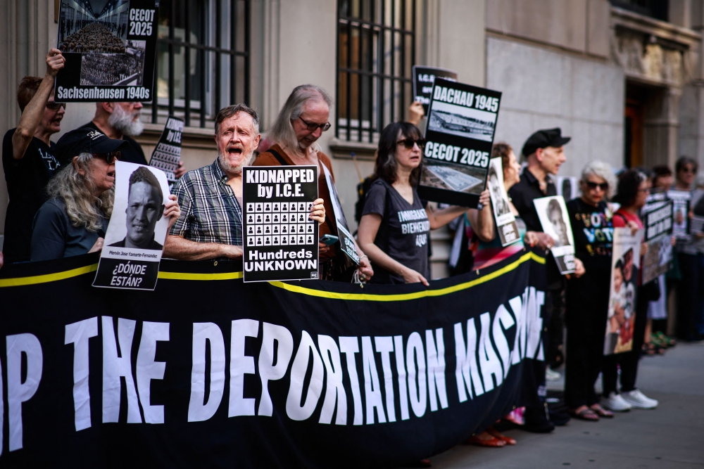 People hold signs and read the names of detainees as they gather, in New York. — AFP