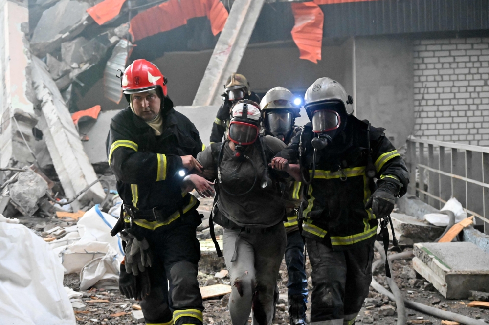 Rescuers help a wounded person walk through the rubble in the Ukrainian city of Kharkiv. — AFP