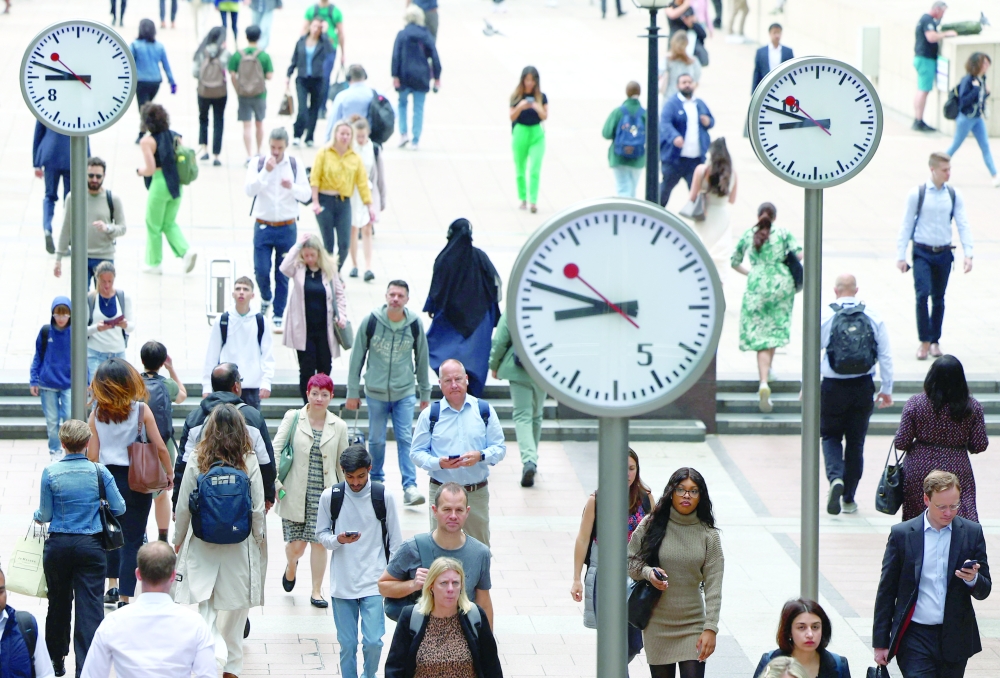 Workers walk through the Canary Wharf financial district in London, Britain. — Reuters