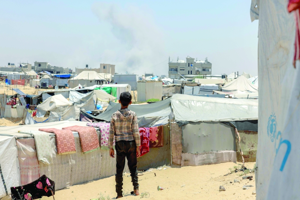 A Palestinian child looks on as smoke billows during Israeli bombardment in Rafah. — AFP