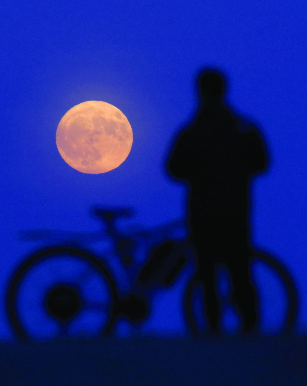 A person watches the Strawberry Moon rise, as seen from Hampstead Heath, in London. — Reuters