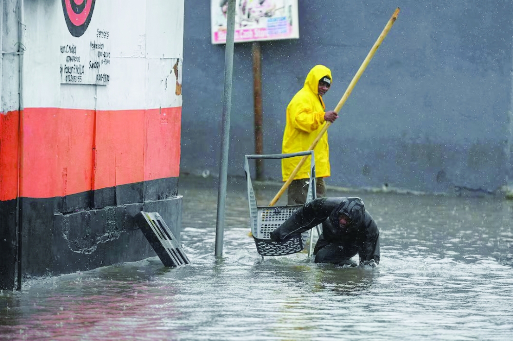 A man stumbles as he tries to cross a flooded road following severe weather, in Cape Town. — Reuters