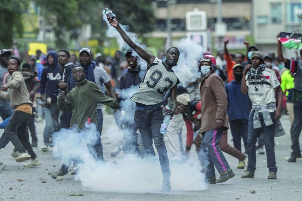  A Kenyan protester returns a teargas