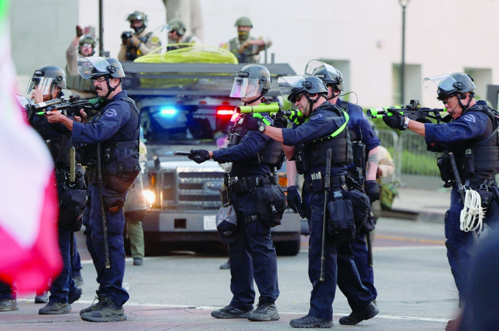 Law enforcement officers shoot non-lethal munitions, as people march as part of the ongoing protests, in Los Angeles. — Reuters 