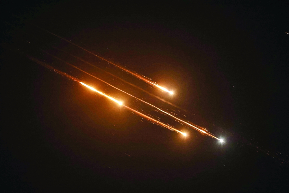 Debris of missiles fired from Iran toward Israel leave trails in the night sky over Nablus in the occupied West bank after being intercepted on Friday. - AFP