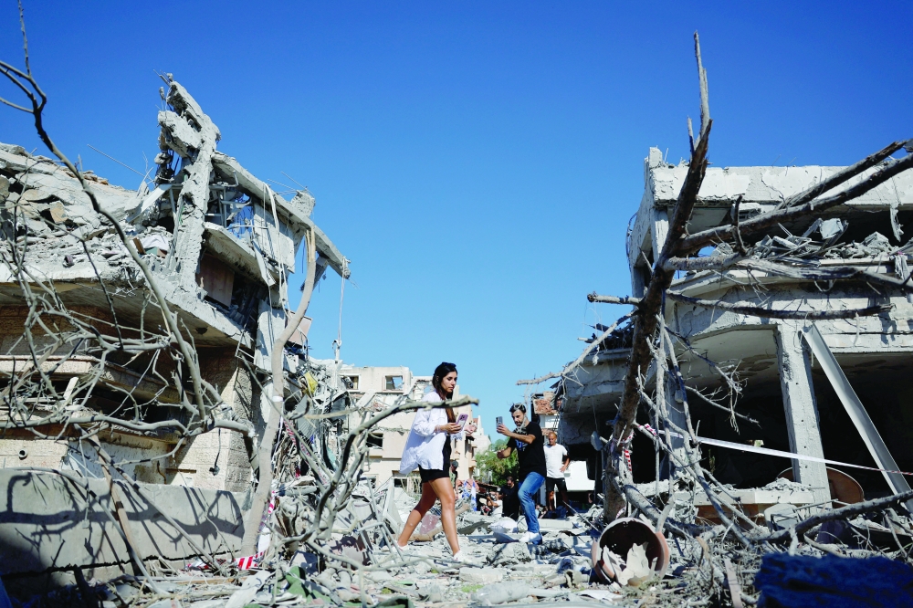 People use their phones at an impact site following Iran's missile attack in Rishon LeZion, Israel, on Saturday. — Reuters