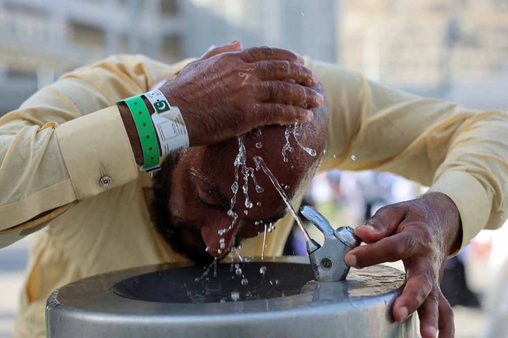 A pilgrim uses a cold water fountain to cool down during the annual haj pilgrimage in Mina. — Reuters file photo