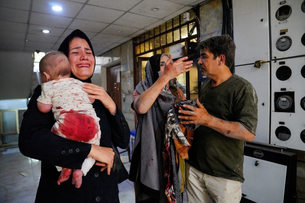 A woman carries her child following the Israeli strikes in Tehran on Sunday. — Reuters