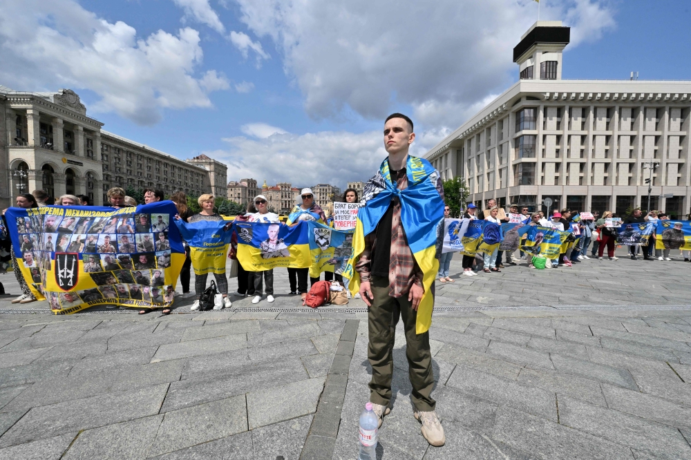 Relatives and friends hold portraits of POWs during rally, in Kyiv. — AFP