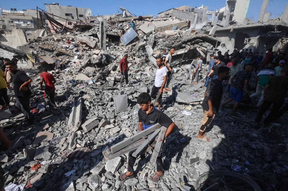 Palestinians salvage items from the rubble of a house hit in an Israeli strike on the Bureij camp. — AFO