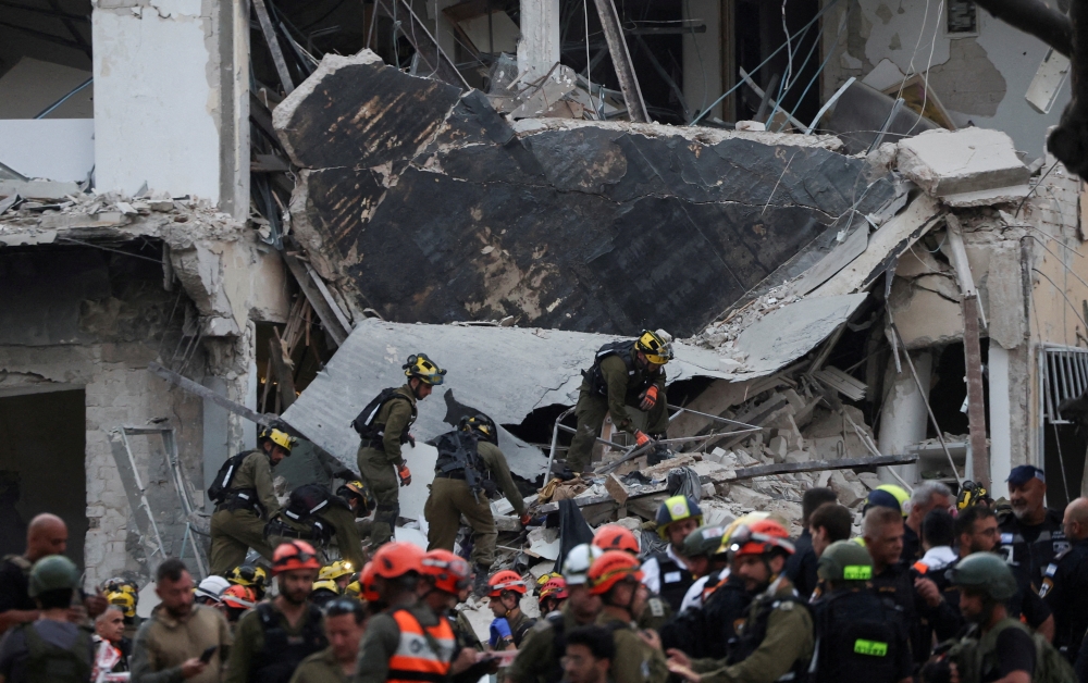 Emergency personnel work at an impact site following Iran's missile attack in Tel Aviv on Monday. — Reuters