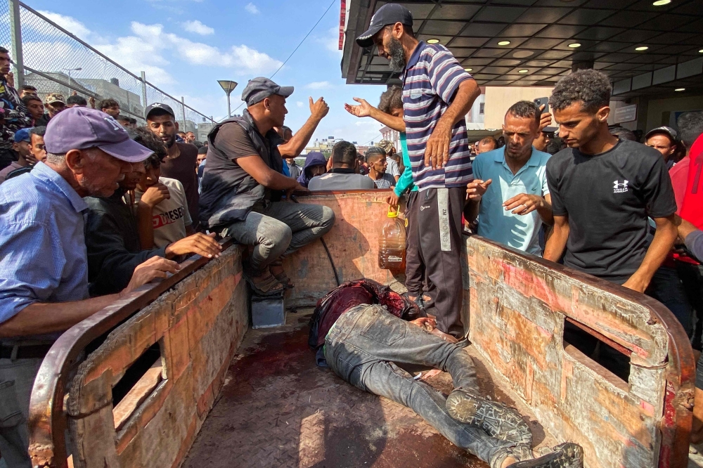 Palestinians transport a man who was injured in Israeli fire while waiting near a food aid centre, into Khan Yunis' Nasser hospital 