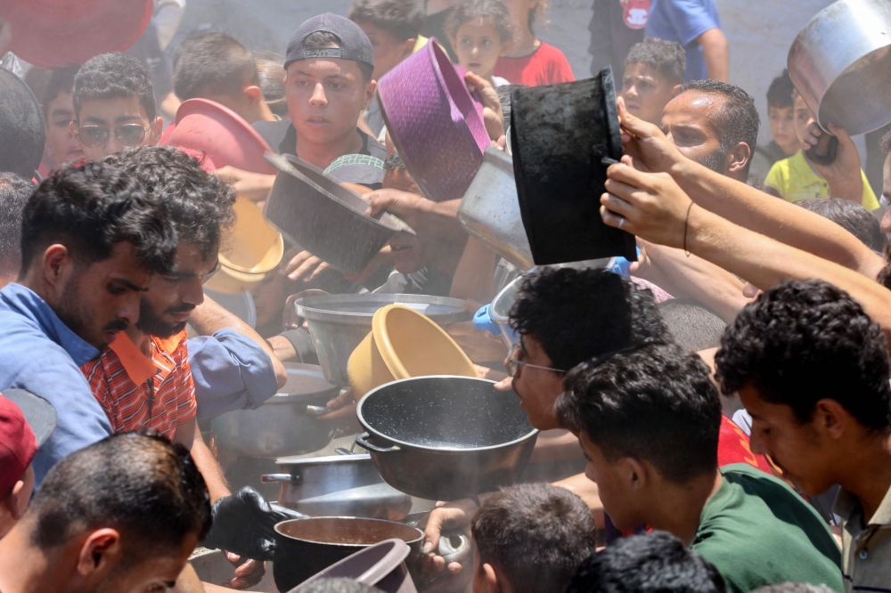 Palestinians try to get food at a charity kitchen in Rimal neighbourhood in Gaza. — AFP