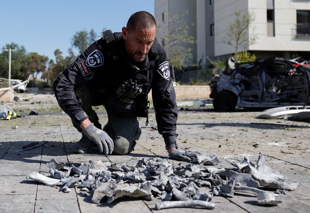 A police officer inspects fragments of missile parts on the ground at an impact site following Iran's missile strike on Israel, in Beersheba, Israel. — Reuters