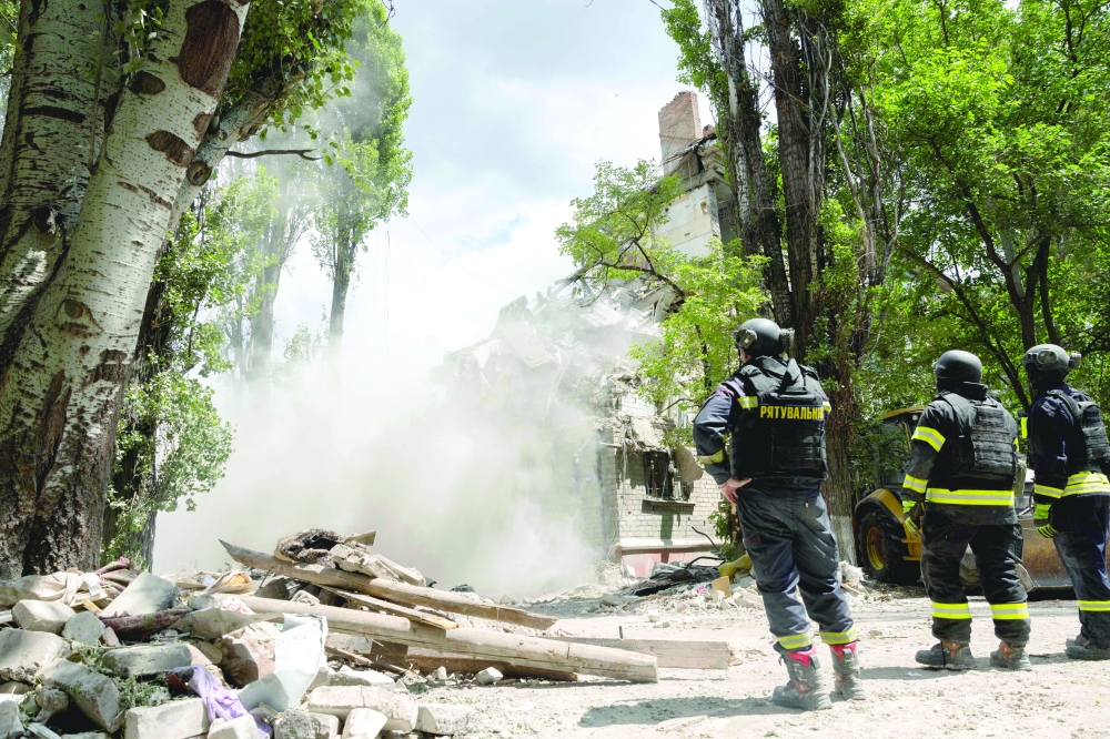 Rescuers stand in front of a damaged building following a Russian strike in Kramatorsk, Ukraine. — AFP