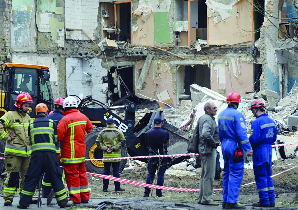Rescuers clear debris a day after a Russian missile strike, in Kyiv. — AFP