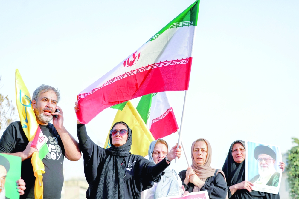 Iranians wave flags and hold a portrait of Ayatollah Ali Khamenei as they celebrate a ceasefire between Iran and Israel, in Tehran on Tuesday. — AFP
