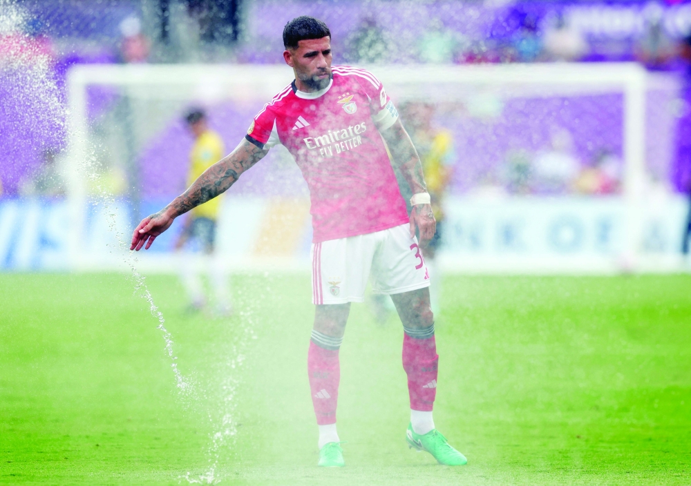 Benfica's Nicolas Otamendi in the sprinklers during a cooling break. —  Reuters