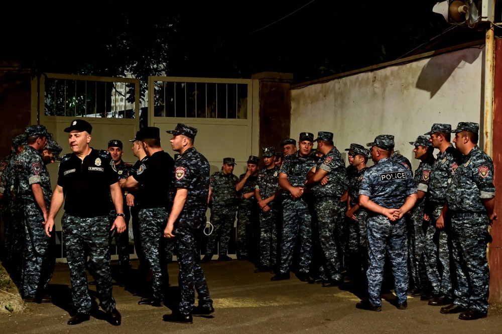 Armenian police officers are seen deployed outside the Avansky court during a rally of supporters of arrested Archbishop of the Armenian Apostolic Church Bagrat Galstanyan, accused of trying to mastermind the attempted coup, in Yerevan on June 25, 2025. (Photo by KAREN MINASYAN / AFP)