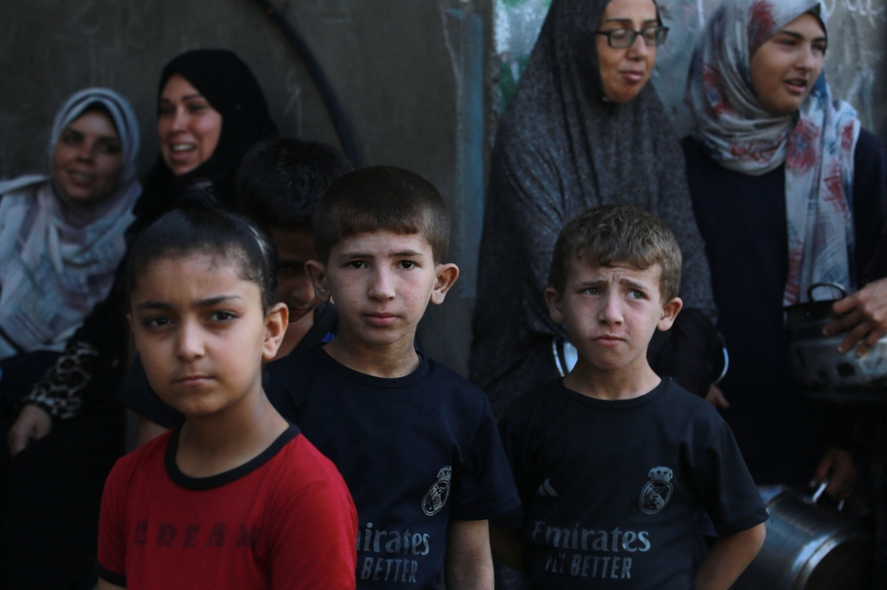 Children line up to receive a meal at a food distribution point in Gaza. — AFP