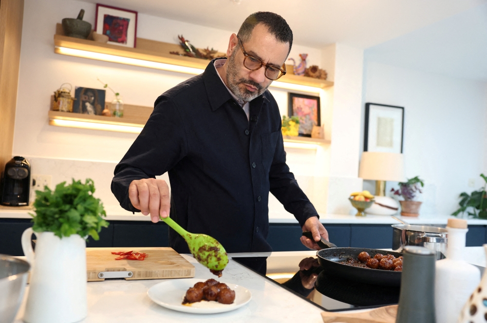 FILE PHOTO: Palestinian-British chef, food-writer and restaurateur Sami Tamimi prepares a dish from his new cookbook during an interview with Reuters at his home in London, Britain, June 3, 2025. REUTERS/Toby Melville/File Photo