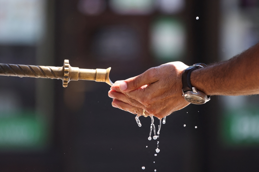 A tourist holds water in his hands at a fountain during a heatwave in Sarajevo, Bosnia and Herzegovina, June 25, 2025. REUTERS/Amel Emric
