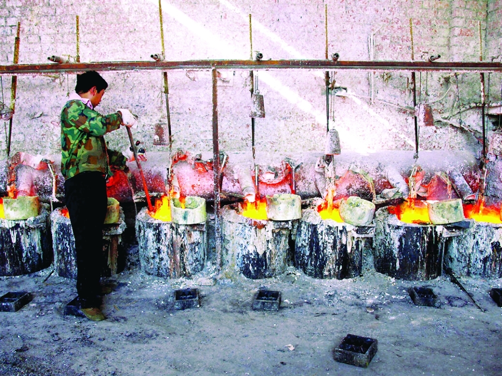 A worker stokes pots containing the rare earth metal lanthanum, near Damao, China. — Reuters