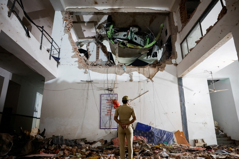A police officer stands in front of the wreckage of an Air India aircraft, in Ahmedabad. — Reuters