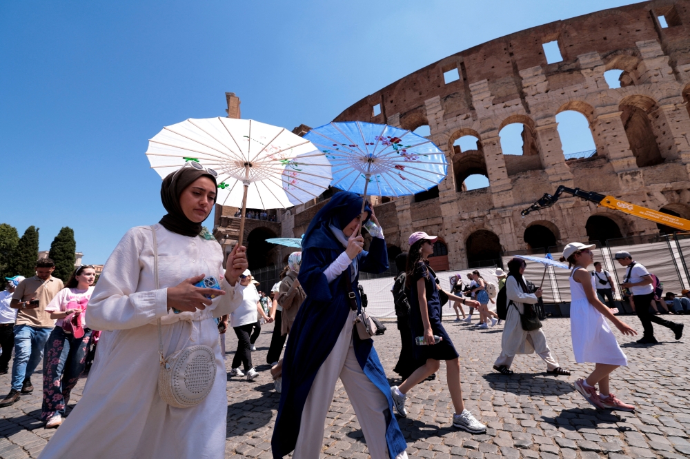 Tourists walk under parasols as they visit the Colosseum during a summer heatwave in Rome. - Reuters 