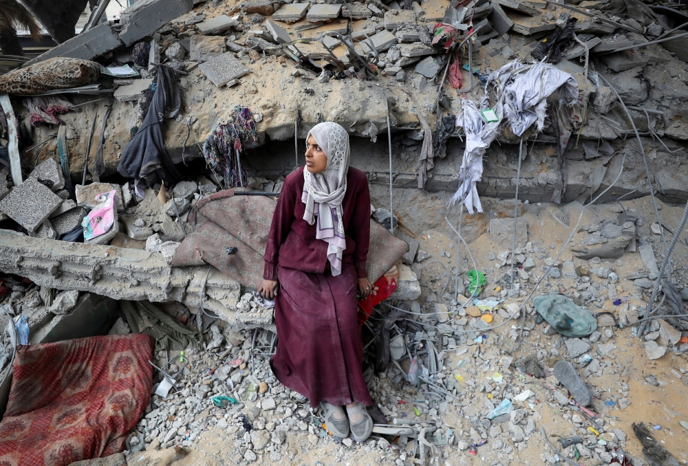 A woman sits amidst the damage at an UNRWA school sheltering displaced people that was hit in an Israeli air strike on Monday. — Reuters